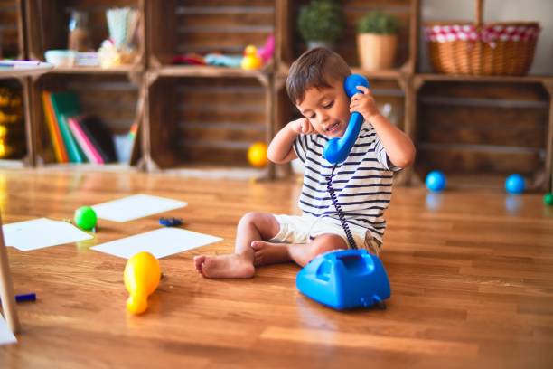 Skaists toddler zēns bērnudārzā spēlējas ar vintage zilu tālruni